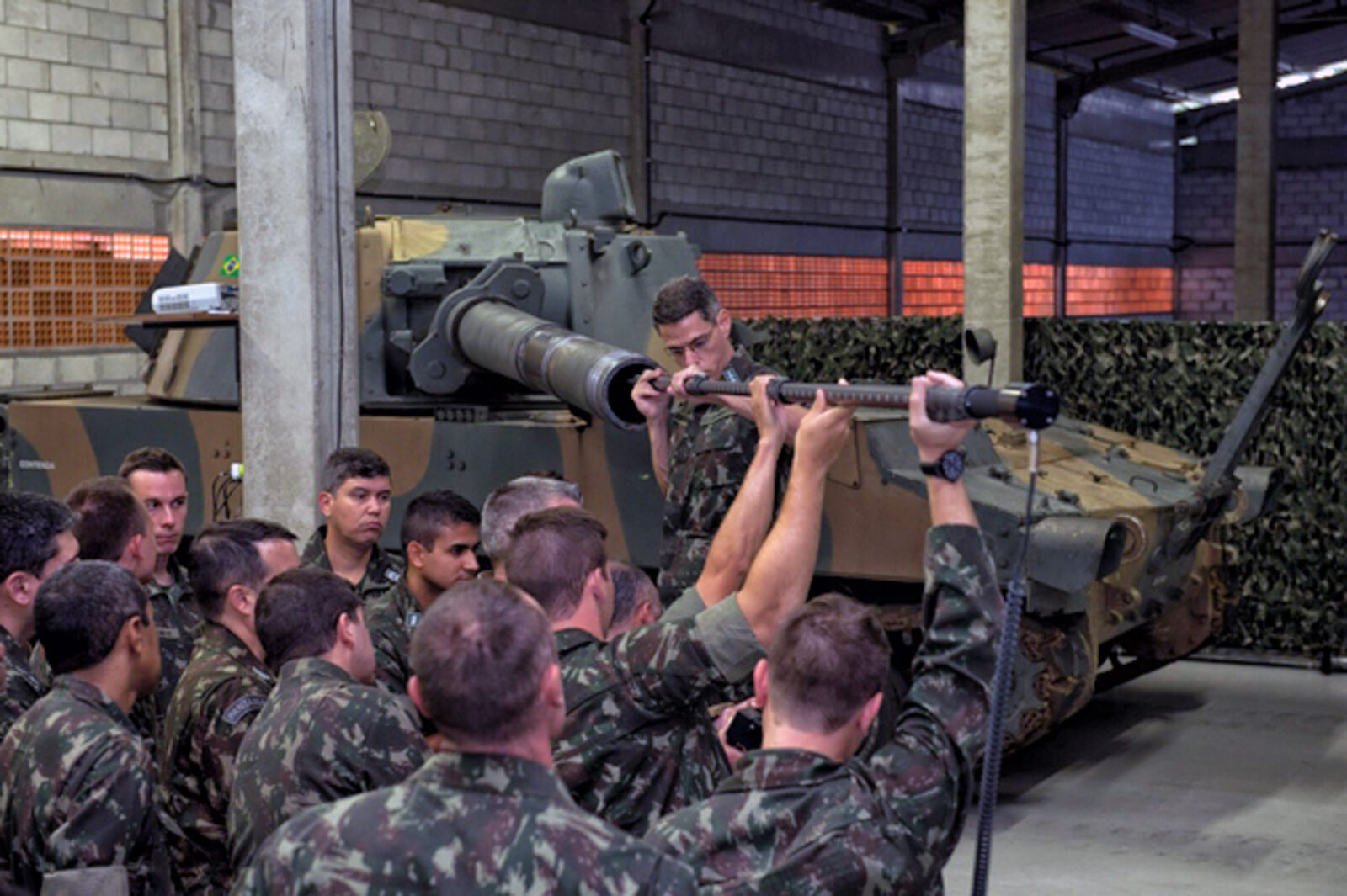 Army maintainers performing a GBIS gun bore inspection on a self-propelled howitzer tube